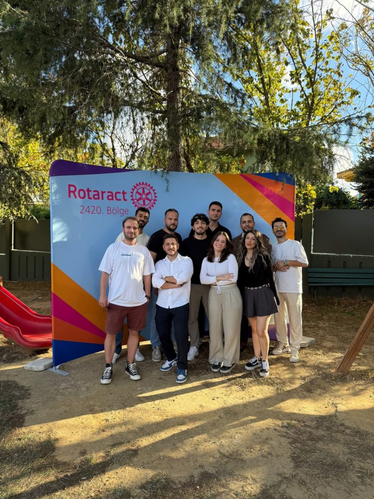 Rotaract 2420. Bölge panosunun önünde poz veren gençler