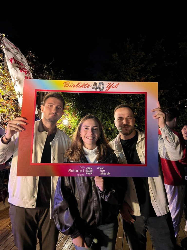Birlikte 40 Yıl yazılı renkli çerçeveyle poz veren üç genç
