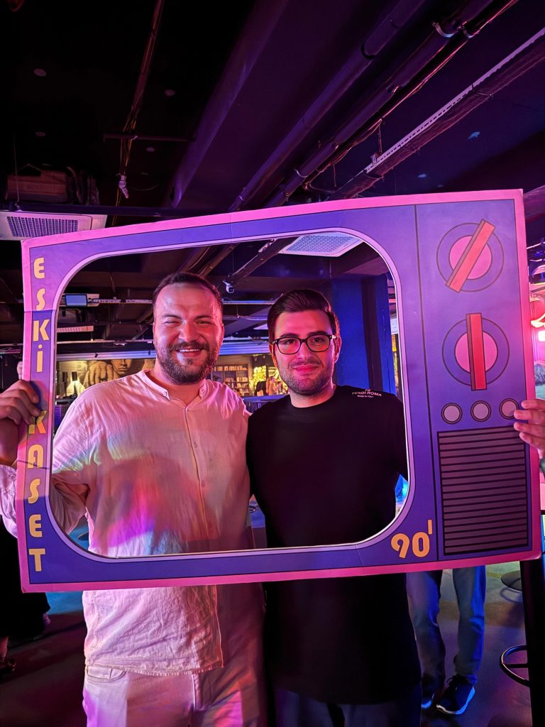 Eski televizyon şeklindeki çerçeveyle poz veren iki genç