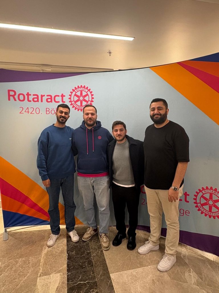 Rotaract 2420. Bölge panosu önünde dört genç