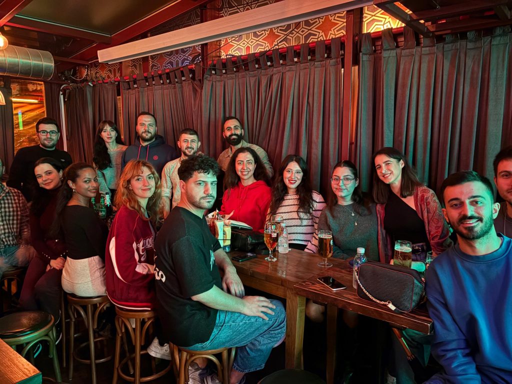 Ahşap masa etrafında gülümseyen kalabalık bir grup