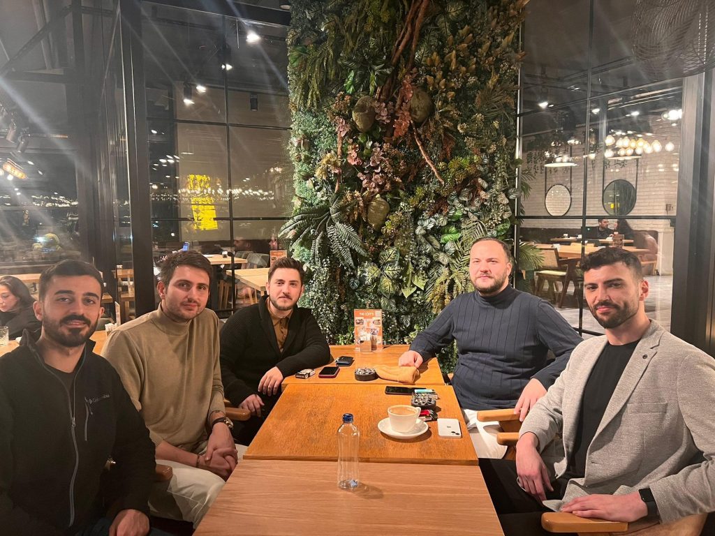 Yeşil duvarlı bir kafede masada oturan arkadaşlar