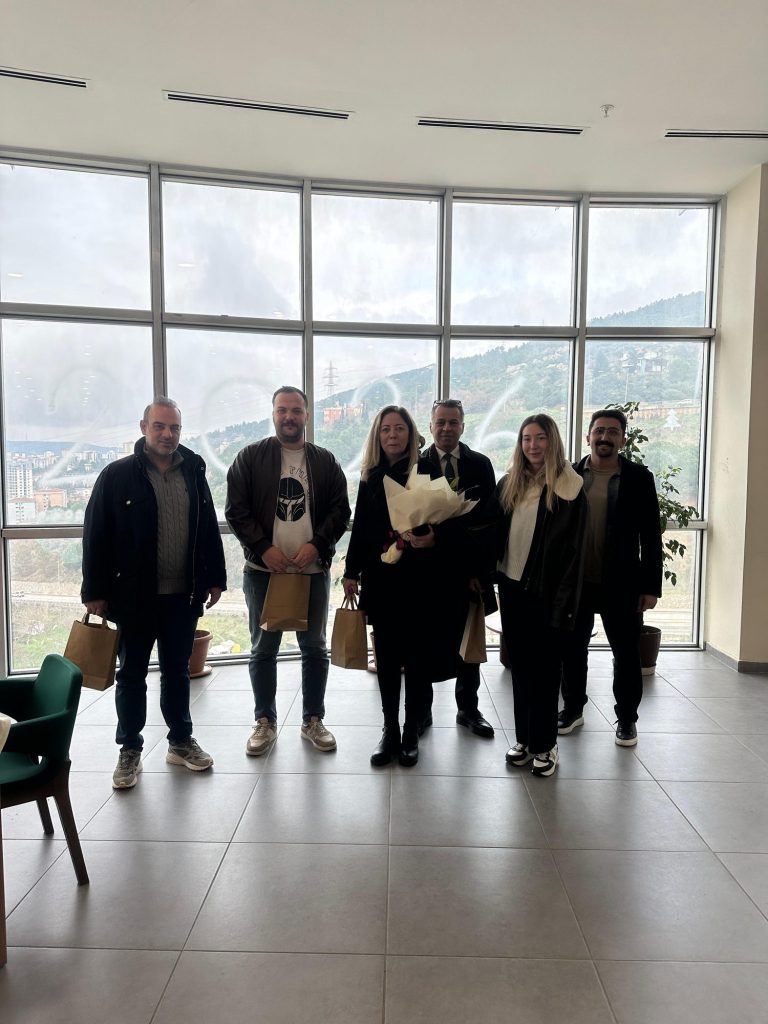 Büyük camların önünde poz veren grup