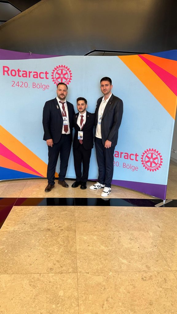 Rotaract 2420. Bölge panosu önünde üç kişi
