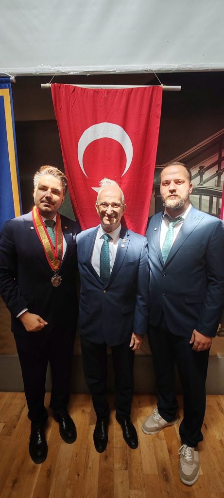 Türk bayrağı önünde takım elbiseli üç kişi
