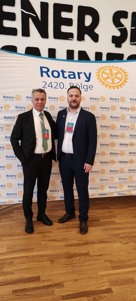 Rotary 2420 panosu önünde iki kişi