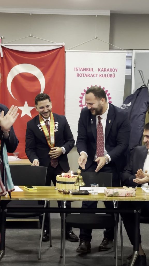 Kulüp bayrağı önünde pasta ve zil başında alkışlayan kulüp üyeleri
